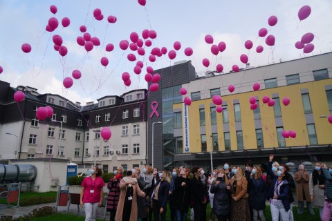 Zdjęcie ukazuje pracowników szpitala, którzy stoją na placu przed budynkiem i wypuszczają do nieba balony
