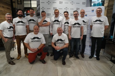 Mężczyźni biorący udział w akcji pozują w białych koszulkach z czarnymi wąsami i napisem Movember